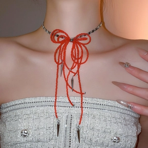 Detail of red beaded bow choker necklace with silver metallic cone pendants