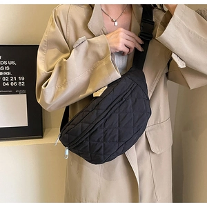 Detail of black quilted crossbody chest bag showing texture and adjustable strap on model