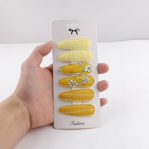 Detailed view of yellow floral and striped fabric hair clips on a white display card