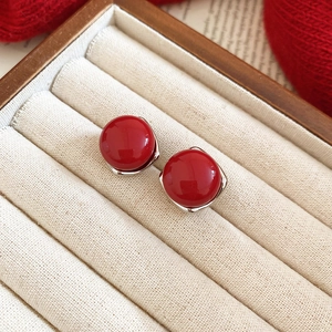 Close-up of red round bead earrings with silver posts in a beige velvet jewelry box