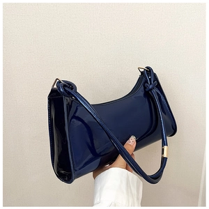 Detail of navy blue patent leather baguette bag featuring glossy finish and gold hardware