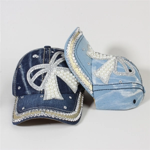 Detail of denim baseball caps with large rhinestone and pearl butterfly bow decorations
