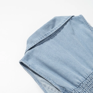 Detail van lichtblauwe denim jurk met omslagkraag en elastisch gesmokte achterkant