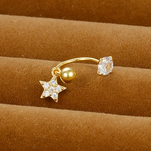 Macro shot of gold-plated stainless steel curved barbell with dangling zircon star charm