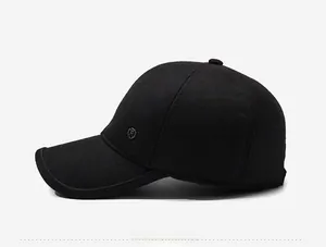 Detail of black winter baseball cap with ear flaps and metal side emblem on wool fabric