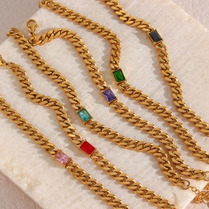 Dettaglio di bracciali a catena cubana dorati con zirconi rettangolari colorati