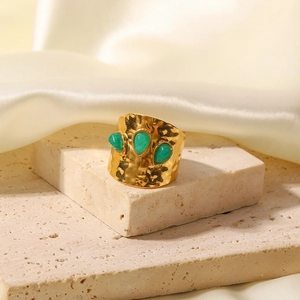 Macro detail of gold hammered ring with three pear-shaped green natural stones on stone