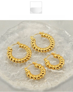 Detailed view of two pairs of gold twisted hoop earrings in different sizes on glass tray