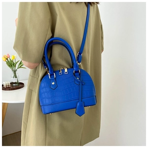 Detail shot of royal blue crocodile pattern shell bag with golden zippers and strap
