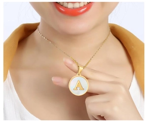 Close-up of gold stainless steel necklace with round shell pendant and letter A charm