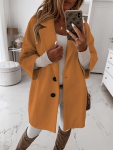 Détail d'un manteau en laine orange ample avec revers classiques et fermeture à boutons