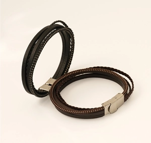 Detail of multi-layer braided leather bracelets in black and brown with silver clasps