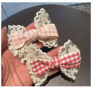 Detail of two handmade floral lace plaid bow hair clips in pink and red cotton fabric