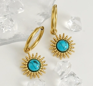Detailed view of gold sunburst earrings with blue turquoise inlay on a clean ice background