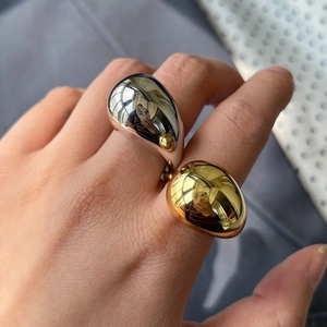 Detail of oversized gold and silver teardrop rings on fingers with mirror polished finish