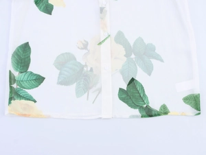 Détail de l'ourlet d'une blouse en mousseline blanche avec imprimé roses jaunes
