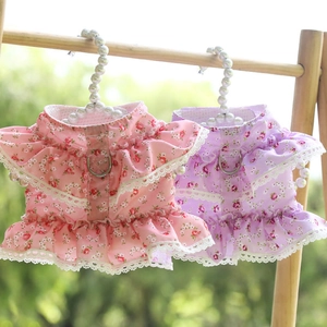 Detailed view of pink and purple floral pet dresses with lace trim and metal leash D-rings