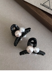 Détail de petites pinces à cheveux noires avec perles blanches et roses sur acrylique chic