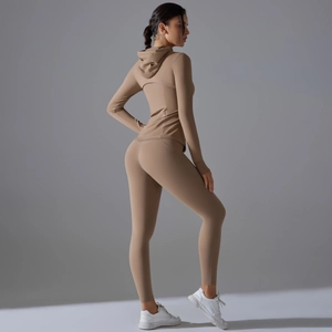 Vista laterale di giacca sportiva con cappuccio beige e leggings a vita alta in studio