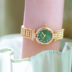 Elegant women's gold quartz watch with a green dial worn on a wrist in soft lighting