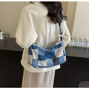 Détail du sac bandoulière en patchwork de denim avec bords effilochés porté par un modèle