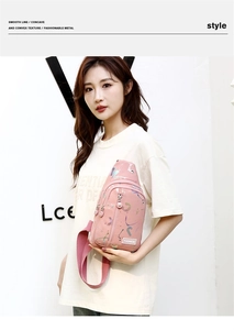 Pink crossbody bag with colorful graffiti and multiple zippers worn by a female model