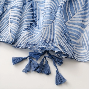 Detail close-up of blue banana leaf pattern fabric with matching tassels for women scarf