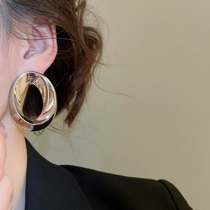 Close-up of model wearing large oval silver metal hoop earrings in minimalist style