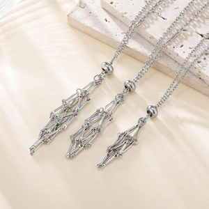 Detail view of silver long chain necklaces with geometric cage pendants and sliding beads