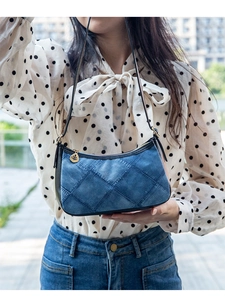 Close-up of quilted denim shoulder bag with golden leaf zipper on a model