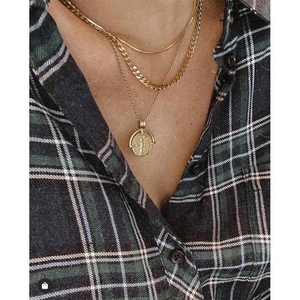 Layered gold-plated snake chain and vintage coin pendant necklace on a model