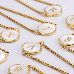 Close-up of 18k gold plated adjustable bracelet with white shell initial letter charms