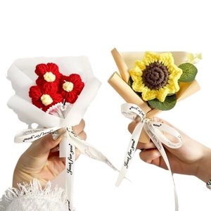 Handcrafted crochet flower bouquets with red blossoms and a yellow sunflower in gift wrap