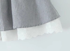 Detailaufnahme des schwarz-weiß gestreiften Stoffes mit feiner weißer Spitzenstickerei am Saum