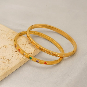 Detail of gold titanium steel bangles with colorful and white zircon stone inlay