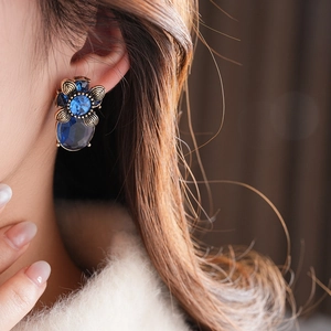 Nahaufnahme der Vintage-Blumenohrringe mit blauem Oval-Edelstein und Golddetails