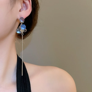 Detail of light blue resin beads and long silver tassel pendant on dangling earring