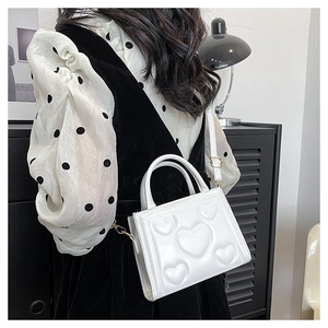 Détail du sac à bandoulière blanc avec motifs cœurs en relief et boucles dorées