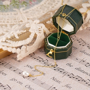 Detail of S925 silver Y-shaped gold necklace with a white pearl in a green jewelry box