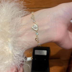 Detailed close-up of golden heart bracelet with white shell inlay and zircon accents