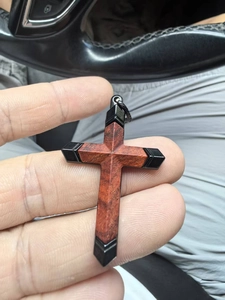 Gros plan d'un pendentif en croix en bois avec détails en métal noir et cordon noir