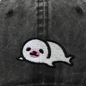 Close-up of cute cartoon seal embroidery on dark grey washed denim baseball cap