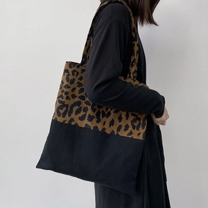 Detailed view of leopard print canvas tote bag with black splicing shown on model