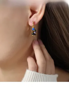 Gros plan de créoles dorées avec perles d'agate colorées style bohème sur un mannequin