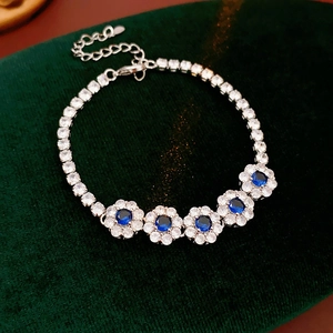 Détail du bracelet fleurs argenté avec zircons bleus sur fond élégant en velours vert foncé