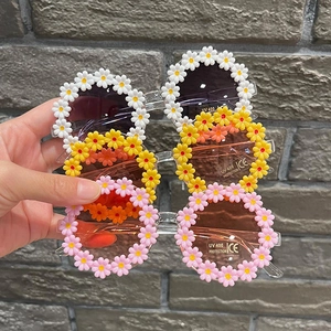 Detailed view of kids daisy flower sunglasses with UV400 protection in white pink yellow