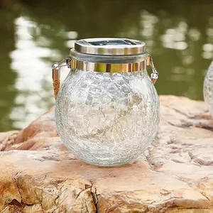 Solar crackle glass jar light with hemp rope handle on a rock by the water
