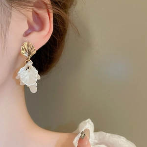 Close-up of French vintage acrylic petal drop earrings with gold shell studs on model