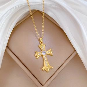 Elegant gold cross pendant necklace with sparkling crystals on a white silk background