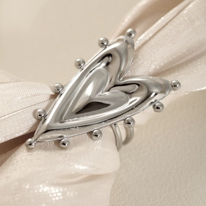 Exaggerated silver stainless steel open heart ring with beaded edges on silk fabric